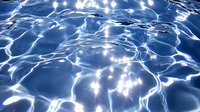 Shimmering water surface with sunlight reflections creating abstract patterns of bright ripples and waves in deep blue swimming pool water.