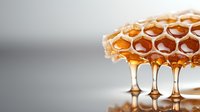 Fresh honeycomb dripping golden honey with hexagonal cells on neutral background for natural food and wellness concepts.