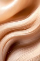 Smooth flowing waves in soft caramel and cream tones create an elegant abstract background pattern with gentle curves and silky texture for luxury designs.
