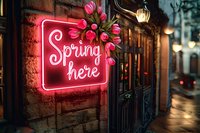 Pink neon sign reading spring here with tulip decoration on brick wall exterior of shop at dusk, glowing street lamps create atmospheric evening ambiance.