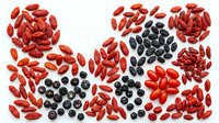 Red goji berries and black goji berries arranged in clusters on white background, isolated dried fruit ingredients for health supplements and wellness products.