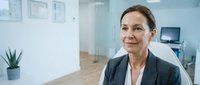 Professional middle-aged Caucasian businesswoman in modern office environment looking confidently ahead with natural lighting and contemporary workspace.