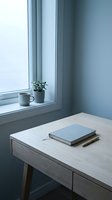 Minimalist workspace with light wood desk, closed notebook, pen, and potted plant on windowsill with mug. Serene home office or study room setup for productivity and creative work.
