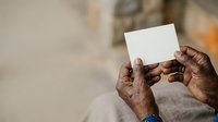 Close-up of hands holding blank white card or paper, suitable for mockups, advertising campaigns, and promotional materials.