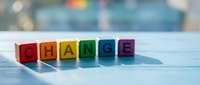 Colorful wooden blocks spelling CHANGE arranged on white surface with soft bokeh background. Business transformation and personal development concept.