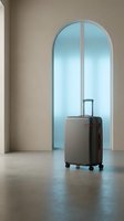 Modern gray suitcase with wheels standing in minimalist interior with arched doorway and soft natural lighting for travel and vacation concepts.