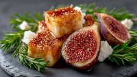 Gourmet cheese cubes with fresh figs and rosemary on dark slate board. Elegant appetizer platter for holiday entertaining and fine dining presentations.