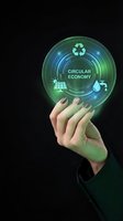 Hand holding glowing circular economy holographic interface with recycling symbol, solar panels, and water drop icons on dark background for sustainability concepts.