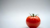 Fresh red ripe tomato isolated on white background for healthy cooking and nutrition concepts.