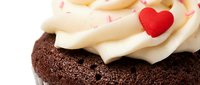 Rich chocolate cupcake topped with creamy vanilla frosting and red heart decoration for Valentine's Day celebration, romantic dessert treat.