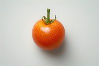 Fresh ripe tomato with water droplets and green stem isolated on white background, ready for food photography and design projects.