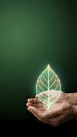Hands holding glowing leaf hologram on green background representing environmental protection, sustainability and eco-friendly business concepts.
