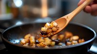 Sautéed mushrooms being stirred with wooden spoon in cast iron skillet for gourmet cooking and culinary preparation in modern kitchen.