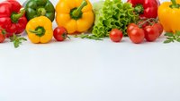 Fresh colorful vegetables including bell peppers, tomatoes and lettuce arranged on white background with copy space for healthy eating and cooking concepts.