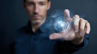Caucasian businessman in dark shirt touching futuristic holographic interface with glowing digital circle projection, concept of future technology and innovation.