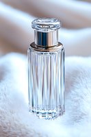 Crystal glass perfume bottle with silver cap on white fur background, elegant luxury fragrance container with vertical faceted design and metallic details.