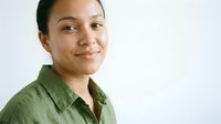 Young mixed-race woman in green shirt smiling confidently at camera against white background for professional headshot and business portrait use.