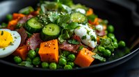 Fresh salad with boiled eggs, sweet potato cubes, green peas, sliced jalapenos and herbs served on black plate, close up view of healthy meal preparation.