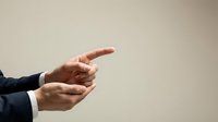 Professional businessman hands pointing forward in suit jacket against neutral background for business presentations and corporate communications.