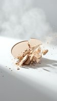Broken beige face powder compact with scattered particles and crumbs on white surface with soft natural lighting for beauty and cosmetics content.