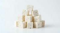 Stacked cubes of crumbly white cheese with visible herbs and seasonings on isolated white background, ready for food and culinary design use.