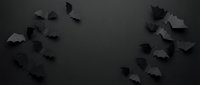 Black paper bats scattered on dark background creating spooky Halloween atmosphere for seasonal decorations and party designs.