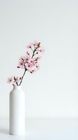 Cherry blossom branch in a white ceramic vase on a light background, minimalist spring decor with delicate pink flowers.