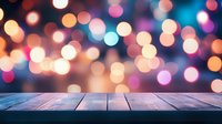 Rustic wooden table surface against blurred festive bokeh lights background in pink, orange and blue colors creating magical holiday atmosphere.