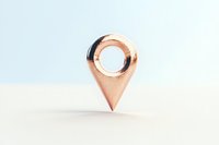 Metallic rose gold location pin marker on white surface with soft shadows, minimalist composition for business and navigation concepts.