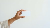 Hand holding blank white card isolated on light background, ready for mockup designs, branding presentations, business cards, and promotional materials.