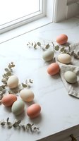 Pastel colored Easter eggs with eucalyptus branches arranged on marble surface near window for spring holiday decoration and seasonal crafting projects.