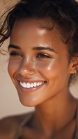 Young mixed-race woman with glowing dewy skin and radiant smile showcasing natural beauty and healthy skincare routine in warm golden lighting.