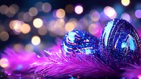Festive blue glitter Christmas ornament on purple feather with magical bokeh lights background creates dreamy holiday atmosphere.
