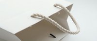White paper shopping bag with twisted rope handles on clean background for retail packaging and branding applications.