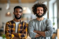 Two confident young men with crossed arms smiling in modern office space. Professional teamwork and collaboration concept for business presentations.