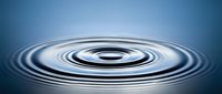 Concentric water ripples creating perfect circular waves on calm blue surface with smooth gradient background for meditation and wellness concepts.
