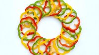 Sliced bell peppers in red, yellow, and green arranged in a circular pattern on white background, isolated and ready for culinary design projects.