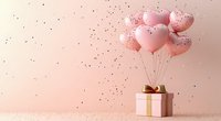 Pink heart balloons floating above gift box with golden ribbon on soft pink background with scattered confetti for romantic celebrations.