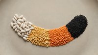 Colorful legumes and beans arranged in curved rainbow pattern on neutral background showcasing variety of protein-rich foods for healthy cooking and nutrition.