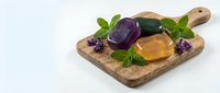 Natural honey jar with fresh lavender flowers and mint leaves on rustic wooden cutting board isolated on white background for organic food design.