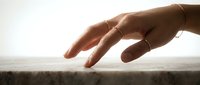 Elegant female hand with delicate gold rings reaching gracefully in warm sunlight, symbolizing connection, aspiration, and gentle human touch in serene moment.
