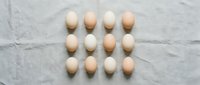 Fresh brown chicken eggs arranged in neat rows on white marble surface for cooking and baking recipes.