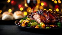 Glazed roasted duck breast with kumquats, grapes and herbs on dark plate against festive bokeh lights background, close up view of gourmet holiday dinner.