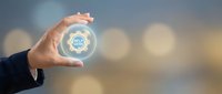 Businessperson holding glowing gear icon symbolizing innovation, technology, and digital transformation in corporate environment for business solutions.
