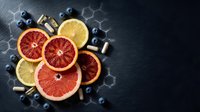 Fresh citrus slices with blueberries and vitamins on dark slate background for healthy lifestyle and nutrition concepts.