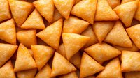 Golden fried samosa pastries arranged closely together, showcasing crispy triangular snacks with appetizing texture for food and culinary content.