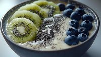 Healthy breakfast bowl with yogurt, fresh kiwi slices, blueberries and chia seeds in dark ceramic bowl, closeup view of nutritious morning meal.