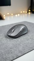 Gray wireless mouse on a fabric pad with warm bokeh lights in a modern workspace setting, suitable for tech and office design projects.