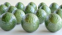 Fresh whole avocados arranged in rows on white background, showing natural green textured skin with water droplets for fresh produce and healthy eating concept.