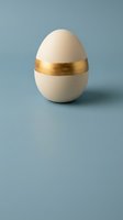 Elegant white egg with golden band on blue background for luxury Easter decoration and premium holiday design concepts.